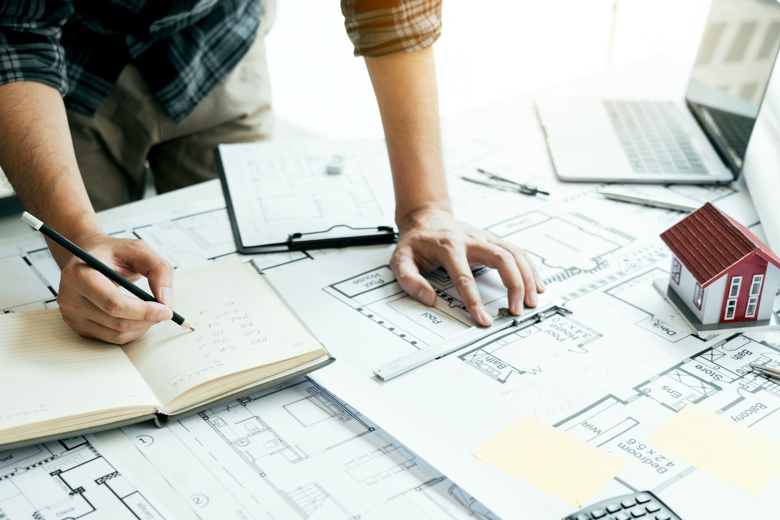 Plans d'architecte et maquette de maison sur une table de travail, projet immobilier en préparation
